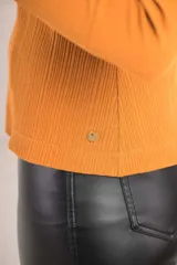 Polera blanca de algodón texturado con cuello alto y mangas largas.