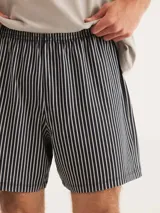 Pijama compuesto por una remera de cuello en V color gris y un short con estampado de rayas verticales en tonos oscuros.