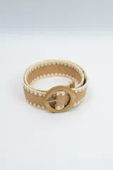 Cinturón de tejido trenzado en color camel con bordes decorativos en hilo color crema y hebilla circular de madera.