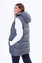 Chaleco puffer largo de color negro, con cierre frontal completo, capucha ajustable con cordones y bolsillos laterales. Diseño acolchado con costuras horizontales.