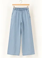 Pantalón de denim claro, con cintura elástica fruncida y corte wide leg de pernera ancha.