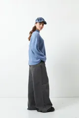 Polera gris de tejido tramado, cuello alto y mangas holgadas.