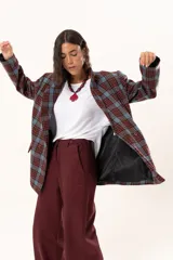 Blazer de corte oversize con estampado de cuadros en tonos azul, bordó y marrón. Presenta solapas clásicas, bolsillos con solapa en el frente y cierre frontal con botones.