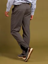 Pantalón de vestir color beige con pinzas, bolsillos laterales y traseros. El ruedo tiene un pequeño corte lateral.