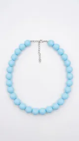 Collar de cuentas esféricas celestes de gran tamaño, con cadena de extensión y cierre metálico plateado.