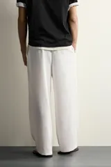 Pantalón relaxed fit de color blanco off-white, confeccionado en tejido con lino. Cuenta con pliegues frontales en la cintura, bolsillos delanteros y cierre frontal con cremallera y botón.