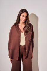 Camisa oversize color marrón, confeccionada en mezcla de viscosa y lino, con cuello clásico, cierre frontal con botones y un bolsillo aplicado en el pecho.