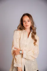 Camisa blanca de broderie, con cuello clásico, cierre frontal con botones, mangas largas abullonadas y puños con botón.