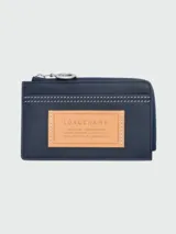 Tarjetero de cuero azul marino Longchamp de la línea Le Pliage Xtra Worker, con cierre superior de cremallera, tarjeteros exteriores y un parche de cuero tostado en el frente con el logotipo de la marca grabado.