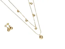 Set de collar doble y caravanas colgantes de acero italiano con baño de oro. El collar tiene dos cadenas con dijes colgantes en forma de bola. Las caravanas también tienen diseño colgante con forma de bola.