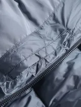 Campera acolchada azul con cuello alto, cierre frontal con cremallera, bolsillos laterales con cremallera, puños y dobladillo con punto canalé y logo de Calvin Klein bordado en el pecho.