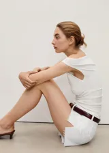 Short de jean blanco con diseño recto, cinco bolsillos, cierre de cremallera y botón, y bajo deshilachado.