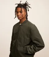 Campera bomber negra para hombre, confeccionada en poliéster con cierre frontal de cremallera, cuello, puños y dobladillo elásticos acanalados, y bolsillos laterales.