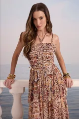 Vestido largo con estampado abstracto en tonos marrones, escote recto con tirantes finos, corte imperio con lazo ajustable en la cintura y falda larga con volantes.