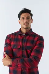 Sobrecamisa de algodón a cuadros color ladrillo, con interior de corderito, cierre con botones, bolsillos tipo cartera y logo en goma. El modelo usa talle M.