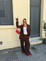 Conjunto de dos piezas compuesto por un blazer y un pantalón de corte sastrero, confeccionados en tela de algodón con estampado de rayas verticales blancas sobre fondo gris. El blazer presenta solapas clásicas y cierre frontal, mientras que el pantalón es de tiro medio y pierna recta.