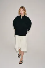 Camisa de cuello redondo y manga corta abullonada, color negro, de corte recto con aberturas laterales y cierre frontal con botones. Perteneciente a la colección ZARA Woman Collection.