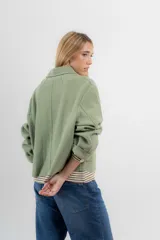 Chaqueta corta tipo blazer color marrón, confeccionada en tela de lana afieltrada. Tiene cuello camisero, silueta cuadrada, cierre frontal con botones y bolsillos delanteros.