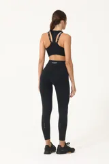 Top deportivo negro con espalda cruzada, elástico inferior y tiras regulables con logo Basset.