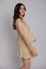Blusa color beige con alforzas en la parte delantera y trasera, cuello redondo y mangas cortas con bordados artesanales.