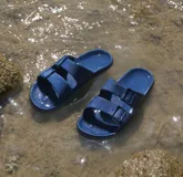 Sandalias planas color ladrillo, con doble tira ancha sobre el empeine y plantilla anatómica. Fabricadas en Brasil con materiales veganos y procesos sostenibles.