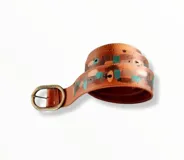 Cinturón ancho de cuero vacuno color terracota, con diseño pintado a mano con detalles en tonos turquesa, marrón y beige. Cuenta con hebilla metálica ovalada en tono oro viejo con grabado de la marca.