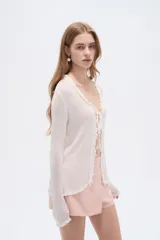 Saco abierto de viscosa color blanco, con cuello en V, lazo para anudar al frente y mangas largas con terminación ondulada.