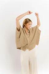 Camisa color crema de lino con mangas amplias y cinta en tono más oscuro en el cuello y la botonadura.