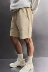 Short jogger marrón de corte relaxed fit, confeccionado en tejido compacto de algodón, con cintura elástica ajustable, bolsillos frontales en la cadera y bolsillo trasero de plastrón.