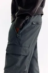 Pantalón cargo gris oscuro de nylon con corte estándar, cintura elástica con cordón ajustable, bolsillos con cierre en los laterales y bolsillos de parche con solapa en las piernas.