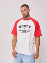 Remera blanca con mangas raglán rojas y estampado frontal con el logo de Rusty en negro.