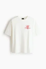 Remera boxy de algodón color blanco, con cuello redondo acanalado, mangas cortas y hombros caídos. Presenta un pequeño estampado rojo en el pecho con las inscripciones 'ROWING CLUB W1F'.