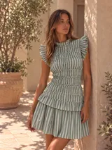 Vestido corto de algodón con estampado de rayas en verde y blanco, cuello alto con volados, cuerpo fruncido tipo smock y falda con volados en capas.