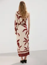 Vestido midi entallado de diseño asimétrico con un solo hombro y una manga larga, confeccionado en color beige con estampado de hojas en tonos bordó. Presenta un cuerpo fruncido y detalle drapeado.