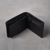 Billetera plegable de eco cuero azul, con múltiples compartimentos para tarjetas, monedero con cierre, tarjetero con visor y dos espacios para billetes. Presenta líneas de pespunte decorativas en la parte superior y el logo de la marca grabado en la esquina inferior.