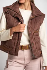 Chaleco acolchado color marrón con cierre frontal y bolsillos laterales.