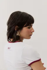 Remera corta gris melange con ribetes amarillos en el cuello y las mangas, y un estampado gráfico abstracto en el pecho.
