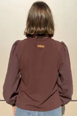 Remera de algodón color azul marino, con cuello redondo fruncido y mangas largas abullonadas con puños elásticos.