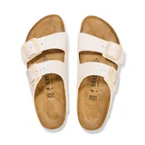 Sandalia Birkenstock modelo Arizona con dos correas ajustables, fabricada en material sintético Birko-Flor color blanco hueso, con plantilla de corcho y suela de goma.