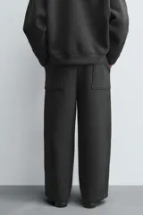 Pantalón de corte wide fit confeccionado en tejido técnico con efecto neopreno. Presenta cintura elástica ajustable con cordón, perneras anchas con costura frontal, bolsillos laterales y bolsillos traseros de plastrón.