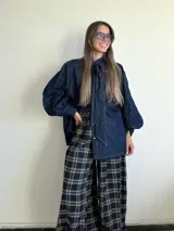 Pantalón de corte amplio y holgado, confeccionado en franela con estampado de tartán escocés en tonos azul, negro y beige. Presenta cintura elástica para un ajuste cómodo.