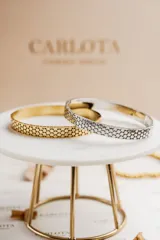 Pulsera rígida dorada con diseño calado, elaborada en acero quirúrgico.