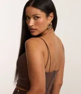 Top cropped color marrón con breteles finos dobles, escote en pico y cierre trasero con cremallera.