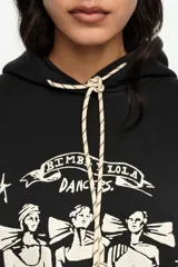 Buzo con capucha color negro, con cordones ajustables crudos y estampado frontal en blanco de bailarinas con la inscripción 'Bimba Y Lola Dancers'.