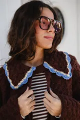Saco tejido en crochet color marrón, con diseño de textura en relieve, manga larga y cuello grande con bordes en color celeste y crema.