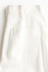 Jean de tiro alto en denim de algodón blanco, con corte de pierna recta, bolsillos delanteros tipo parche y pliegues marcados. Incluye un cinturón estampado con diseño animal print de leopardo.
