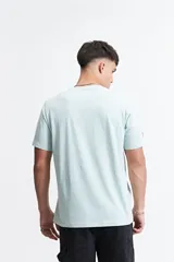 Remera de manga corta color menta, con estampado frontal de un diseño abstracto en tonos grises y azules, y texto. Confeccionada en 100% algodón y de corte regular.