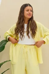 Camisa amarilla de manga larga, con cuello camisero, cierre frontal de botones y corte oversize.