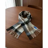 Bufanda rectangular de tejido grueso con diseño de cuadros en tonos azul, naranja, gris y beige, terminada con flecos en los extremos.