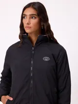 Campera reversible de diseño holgado, con un lado en tejido sherpa estampado con motivos florales en tonos negro y beige, y el otro lado en nylon negro. Cuenta con cierre frontal y cordones ajustables en el ruedo.